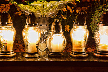 All Saints Day. Candles burning on graves at cemetery at night. All Hallows Eve / Day of All the Saints / Solemnity of All Saints / Feast of All Saints / 1st November / Happy Halloween / 31st October