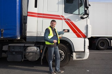 Logistics - proud driver  with tablet computer, in front of trucks .