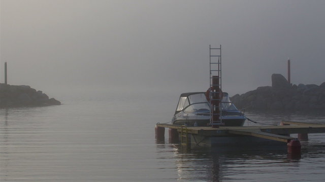 The small port where a small boat is docked in. The place is foggy in a late afternoon time