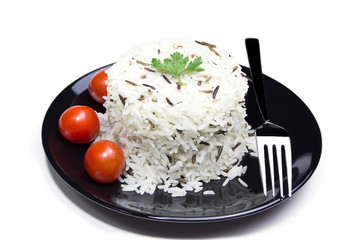 Rice with cherry tomatoes and greens on a black plate
