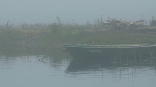A boat docked on the side of the port. It is a long boat with black color and a foggy area of the sea