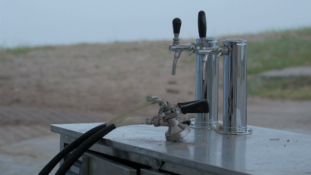 A sink with two faucets on it. The faucet is silver in color with black rubber on them