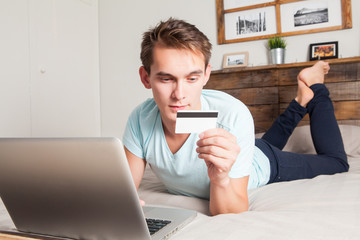 Young man holding a credit card during an e commerce payment. Ho