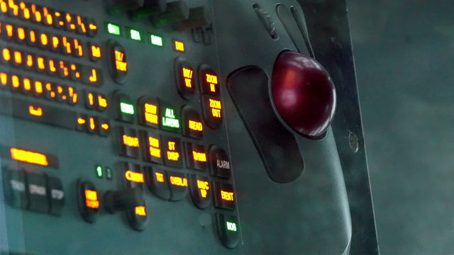 The dashboard of the captains deck. It has lots of buttons in orange color and red siren light on it
