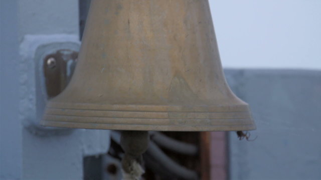 A bell on the ship on the port. The bell is in brown color for a signal in the ship