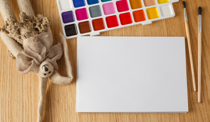 Paints with brush on table with felt cozy doll