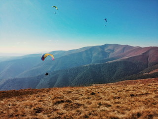 People flying on paragliders above the mountains