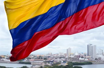 Fototapete Südamerika Kolumbianische Flagge weht im Wind und moderner Stadtteil Cartagena