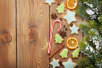 Christmas wooden background with snow fir tree, spices, gingerbr