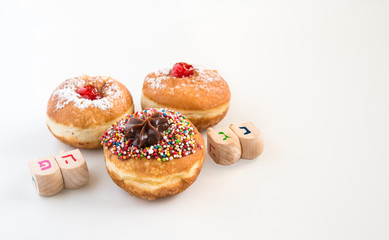 Obraz na płótnie Canvas Close up of fresh donuts and wood dreidels for Hanukkah Jewish Holiday.