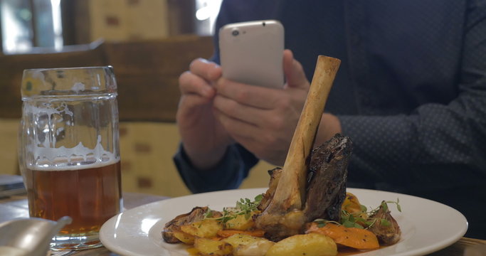 Man with phone making photo of a served dish 