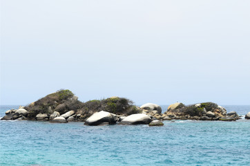 Little rocky island surrounded by turquoise sea water 