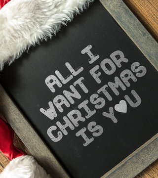All I Want For Christmas Is You written on blackboard with santa hat