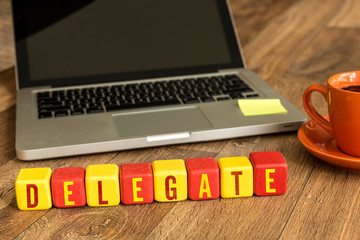 Delegate written on a wooden cube in a office desk