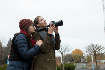 Two girlfriends shooting on the camera in city