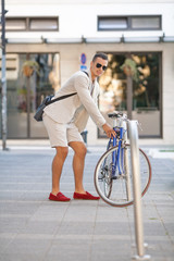 Young man locking his bicycle at the parking on the street