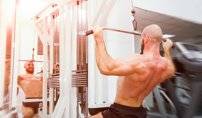 Man doing back pullups in the mirror at the gym with a energy powerful look and feel with soft filters applied suggesting a hard workout - obrazy, fototapety, plakaty