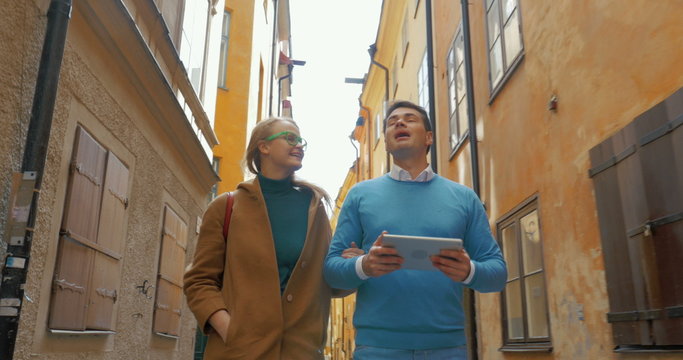 Young couple with pad walking in old narrow street