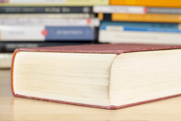 Close-up of book with red cover in front of piles of books
