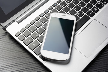 Blank White Business Smartphone With Reflection Lying On A Notebook Keyboard, All Above A Carbon...