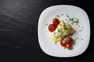 Chicken breast baked with mozzarella cheese and tomatoes on white plate. Top view