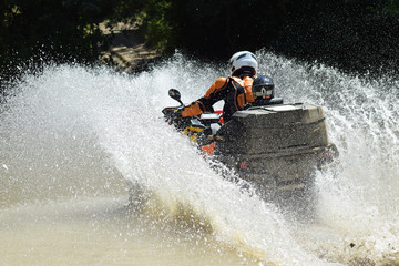The man on the ATV crosses a stream