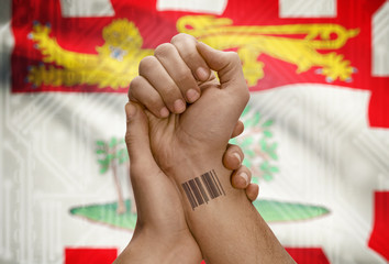 Barcode ID number on wrist of dark skin person and Canadian province flag on background - Prince...