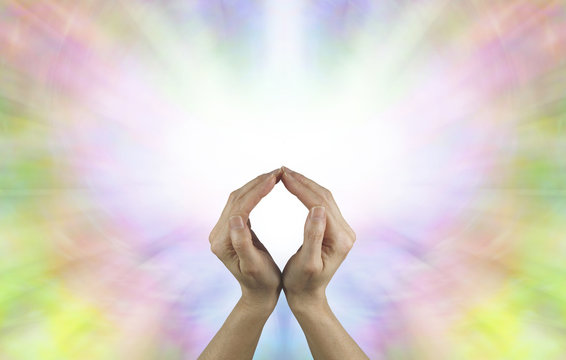 The Circle of Eternal Life - Female hands making an O shape with a vibrant burst of white light energy behind filled by a rainbow colored butterfly shape and plenty of copy space