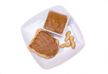 Slice of bread with peanut butter on white background top view