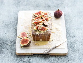 Loaf cake with figs, almond and white chocolate on wooden serving board over grunge background, selective focus