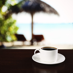 Cup of coffee on table on sea background