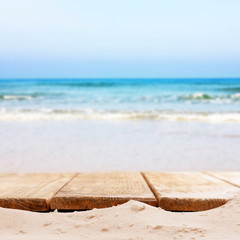Fototapeta na wymiar Sand with wooden planks on sea background