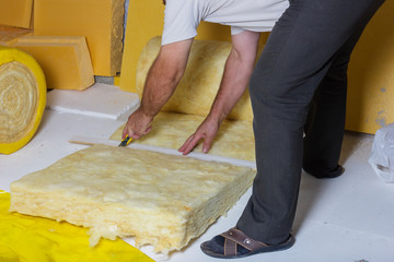 handyman cutting the termal insulation at the attic