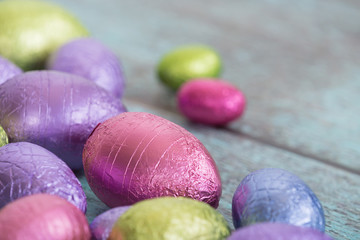 Pastel color Easter chocolate eggs on vintage green wooden background, shallow depth of field