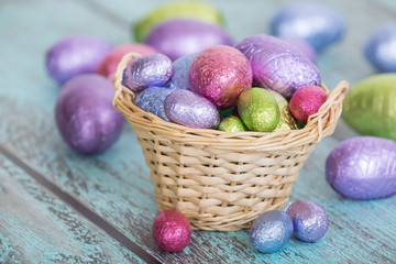 Pastel color Easter chocolate eggs in a basket, vintage green background, shallow depth of field