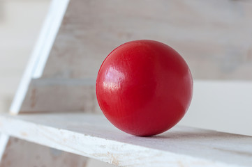 Traditional children's games. Air-filled, elastic red ball, decorative, on white wooden stairs. With empty space for text