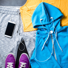Sport clothes, shoes and mobile phone with headphones. Top view