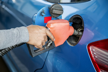 Hand refilling the car with fuel at Petrol pump filling.