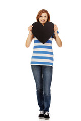 Young teenage woman holding black paper heart