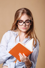 Girl with glasses holds a notebook.