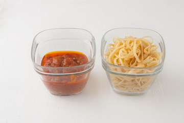 a small portion of linguini pasta and pasta tomato sauce in a glass storage container
