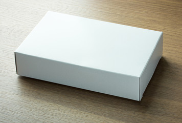 blank white paper box on dark wood background