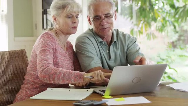 Sweet Senior couple using laptop computer to pay bills