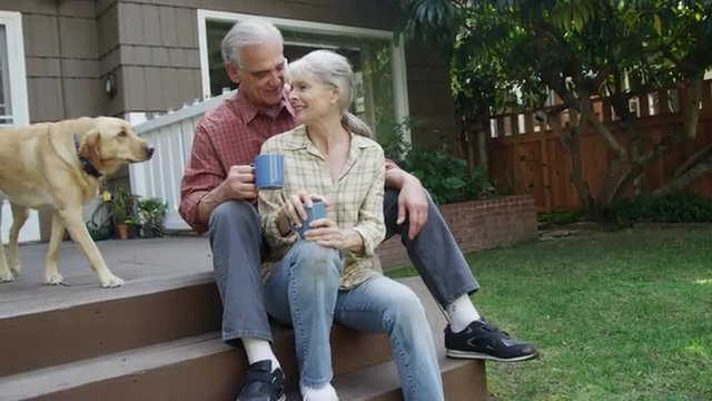 Senior couple having coffee petting dog in their yard