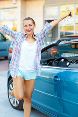 Young emotional woman standing near a convertible with the keys