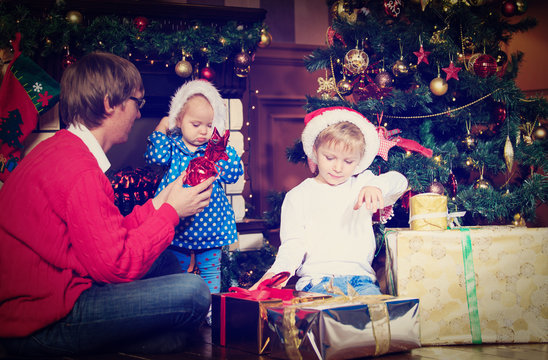 father and kids with presents at christmas