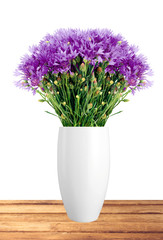 Beautiful violet flowers in vase on wooden table over white