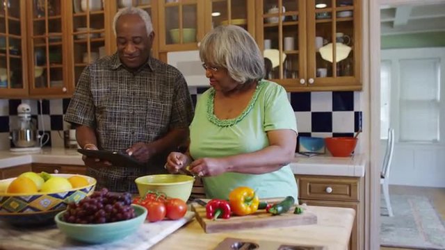 Senior black couple cooking together in kitchen