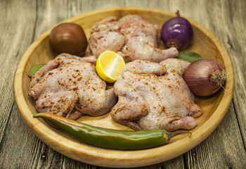 Three fresh raw chicken on a wooden tray with lemon and chilli  on the wooden background