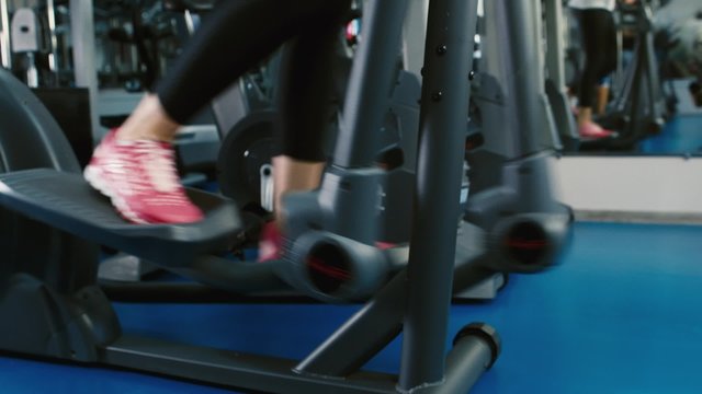 Training in the gym on the elliptical trainer feet